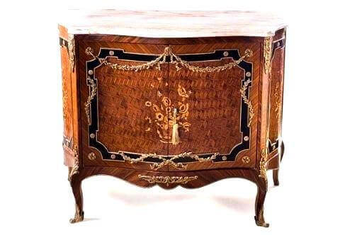 an exquisite 19th century transitional style exotic wood, and ebony inlaid ormolu mounted cabinet. the legs are finished with ormolu sabots. the scalloped apron with an ormolu acanthus leaf motif. the cabinet doors has a parquetry inlay with a floral marquetry motif inlay. the inlay is trimmed with ebony color inlay with a twisted sweeping ormolu garland . the sides of cabinet have parquetry and foliage marquetry inlay. topped with a sensational moulded veined white marble
